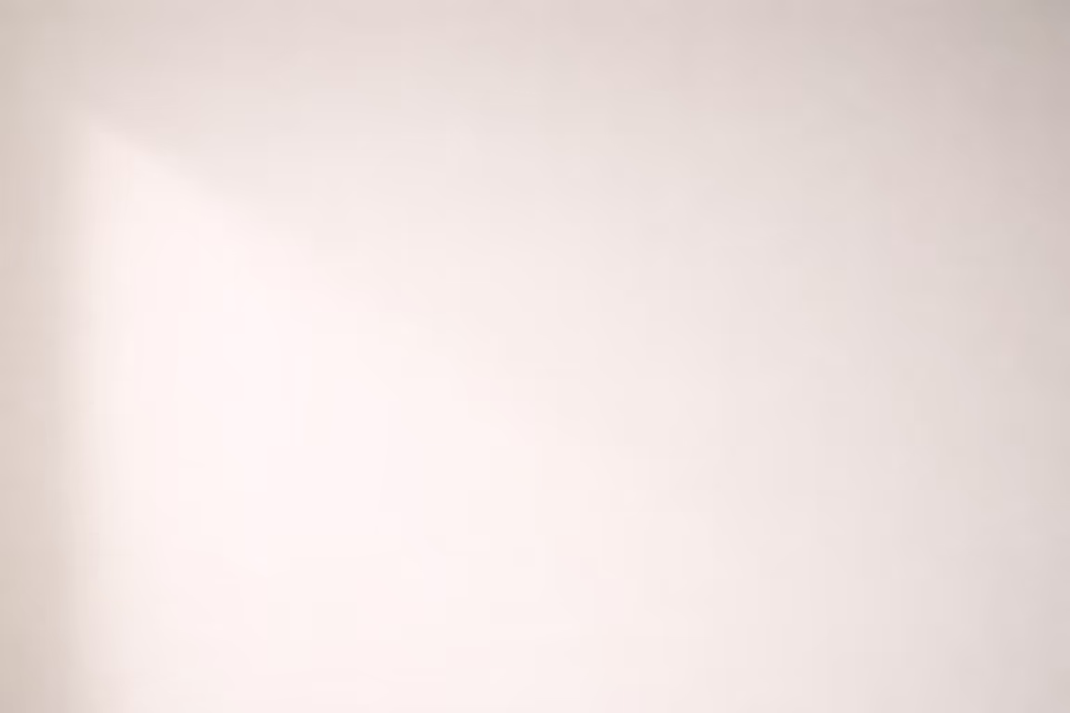 A long pale wall with a single faint shadow gradually fading toward the edge of the frame, photographed in flat diffused light.