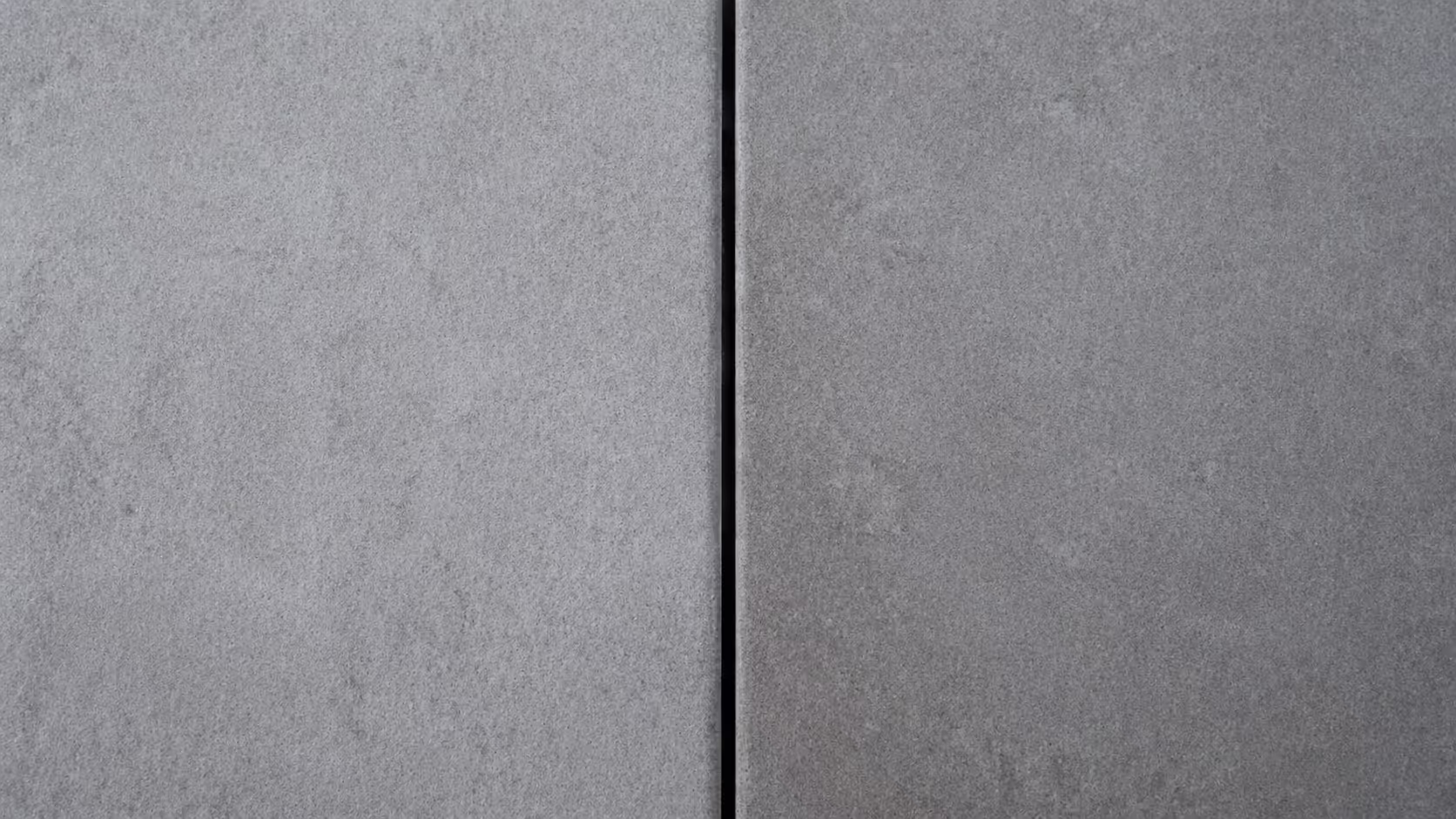 Two flat stone or concrete surfaces placed side by side with a thin, deliberate gap between them, photographed from above in soft diffused light.