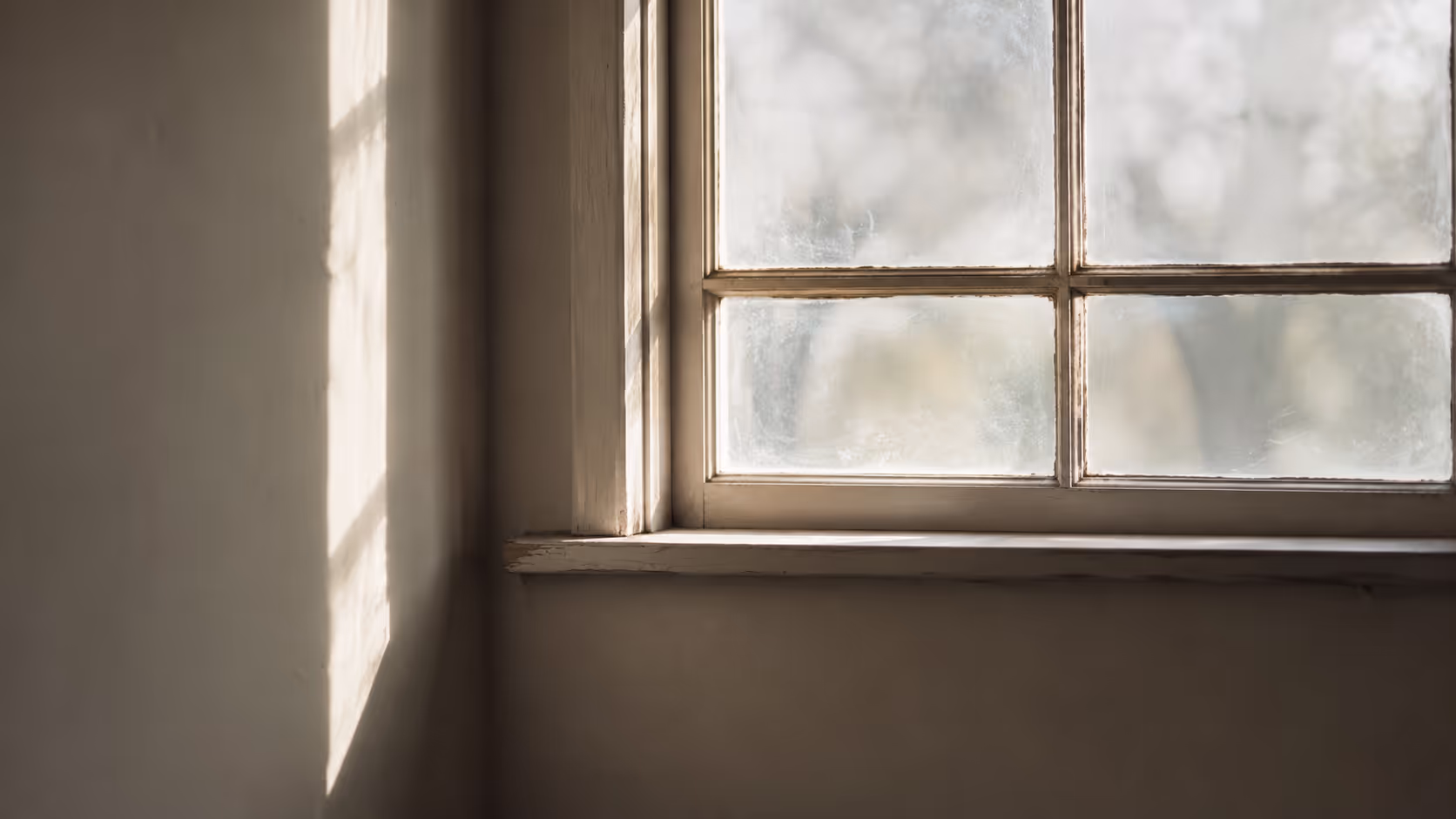 Soft natural light passing through an old single-pane window with subtle imperfections in the glass.