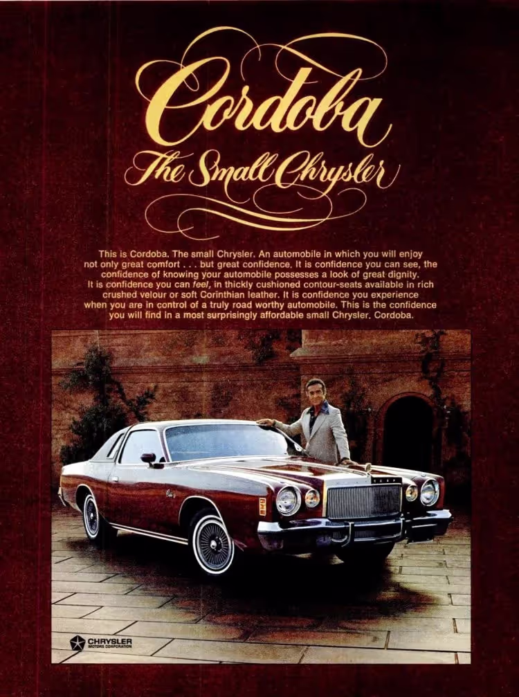 A vintage advertisement for the Cordoba, The Small Chrysler. The ad features a burgundy Cordoba car parked on a paved area in front of a rustic stone building with an arched doorway. A man in a light-colored suit leans casually on the car's hood, smiling. The top of the ad has a dark red background with the car's name 'Cordoba' in large gold cursive script, followed by 'The Small Chrysler.' Below the title, descriptive text about the car's features is present. The Chrysler logo is in the bottom left corner.
