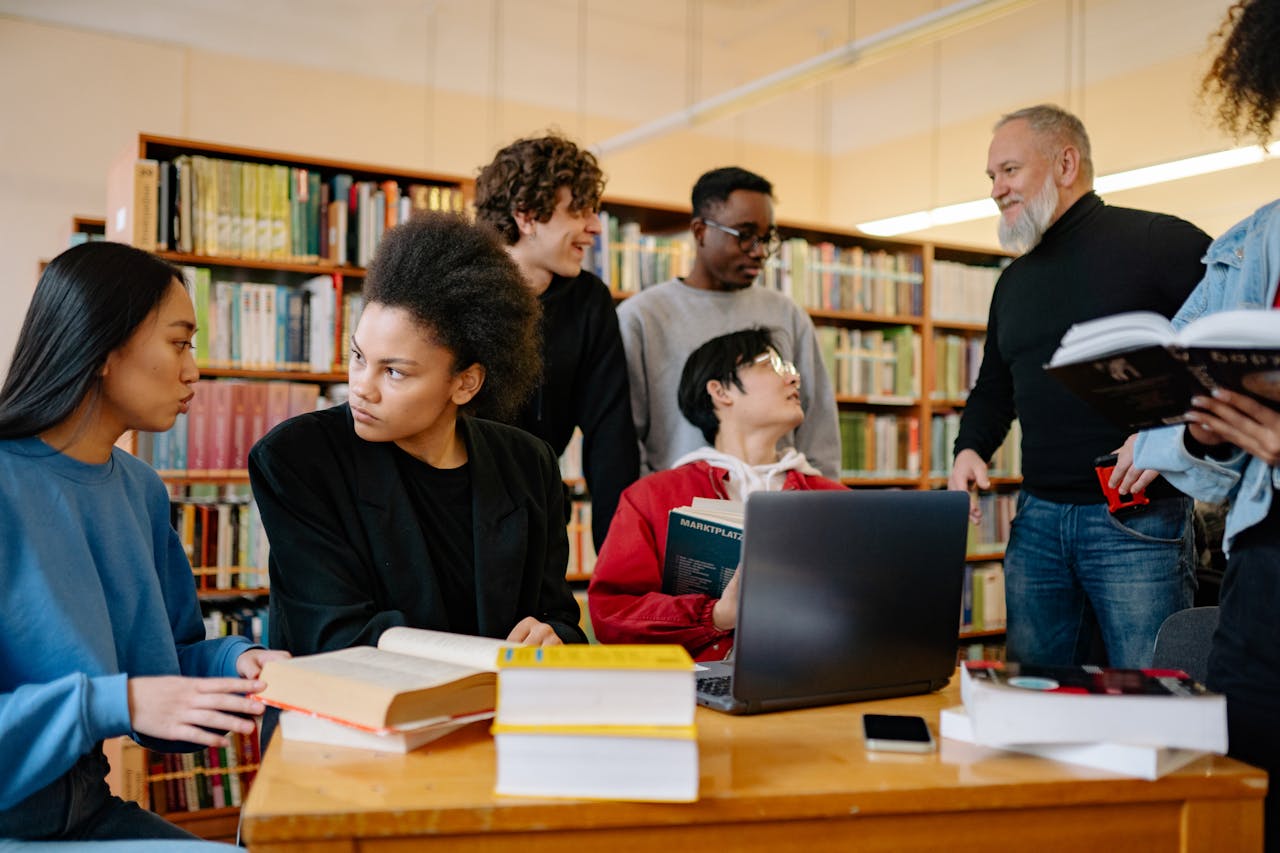 A professor talking to a group of college students, discussing key metrics like retention, graduation rates, and service utilization to measure the effectiveness of college student financial wellness 
