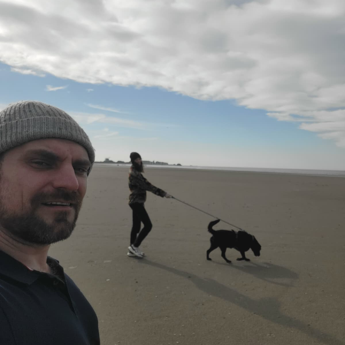 Konrad and Caro walking a chocolate Labrador on the beach