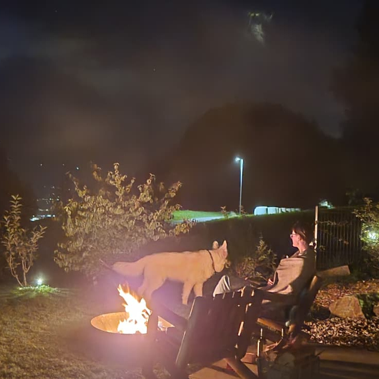 Caro sitting by the fire with a dog we were house sitting in Switzerland