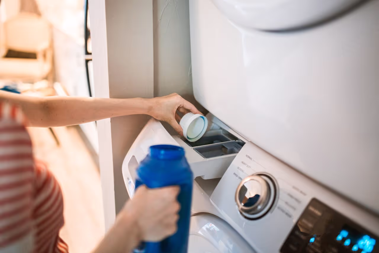 A person pouring washing liquid into the washing machine