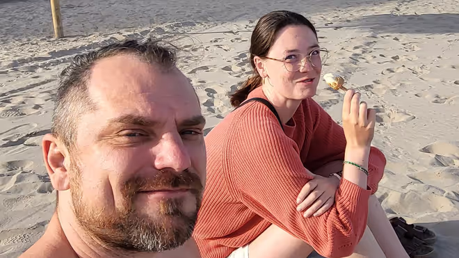 Konrad and Caro sitting on a beach in Portugal