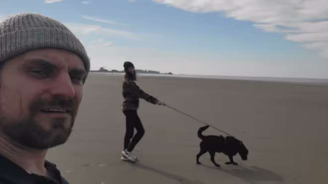 Konrad and Caro walking a dog on the beach Konrad and Caro walking a dog on the beach