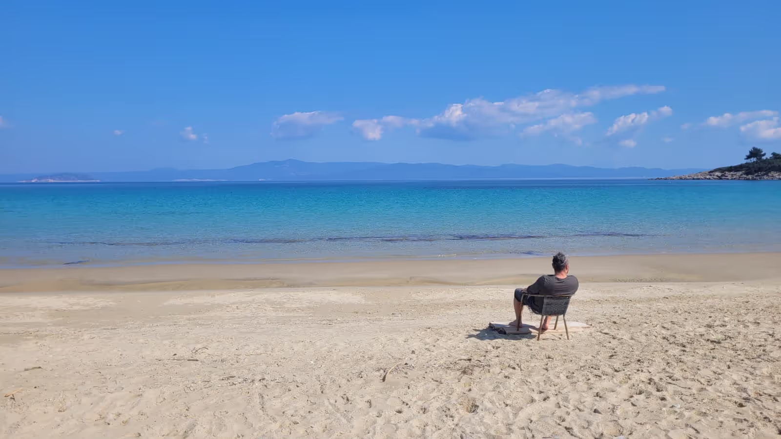 Konrad sitting on a beach in Greece