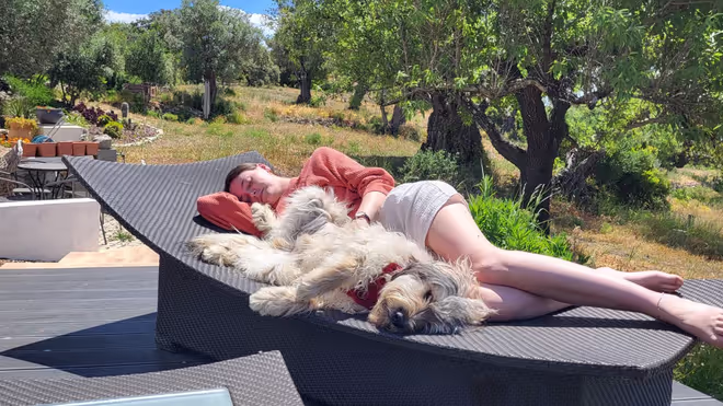 Caro laying besides the dog on a sunbed in Portugal