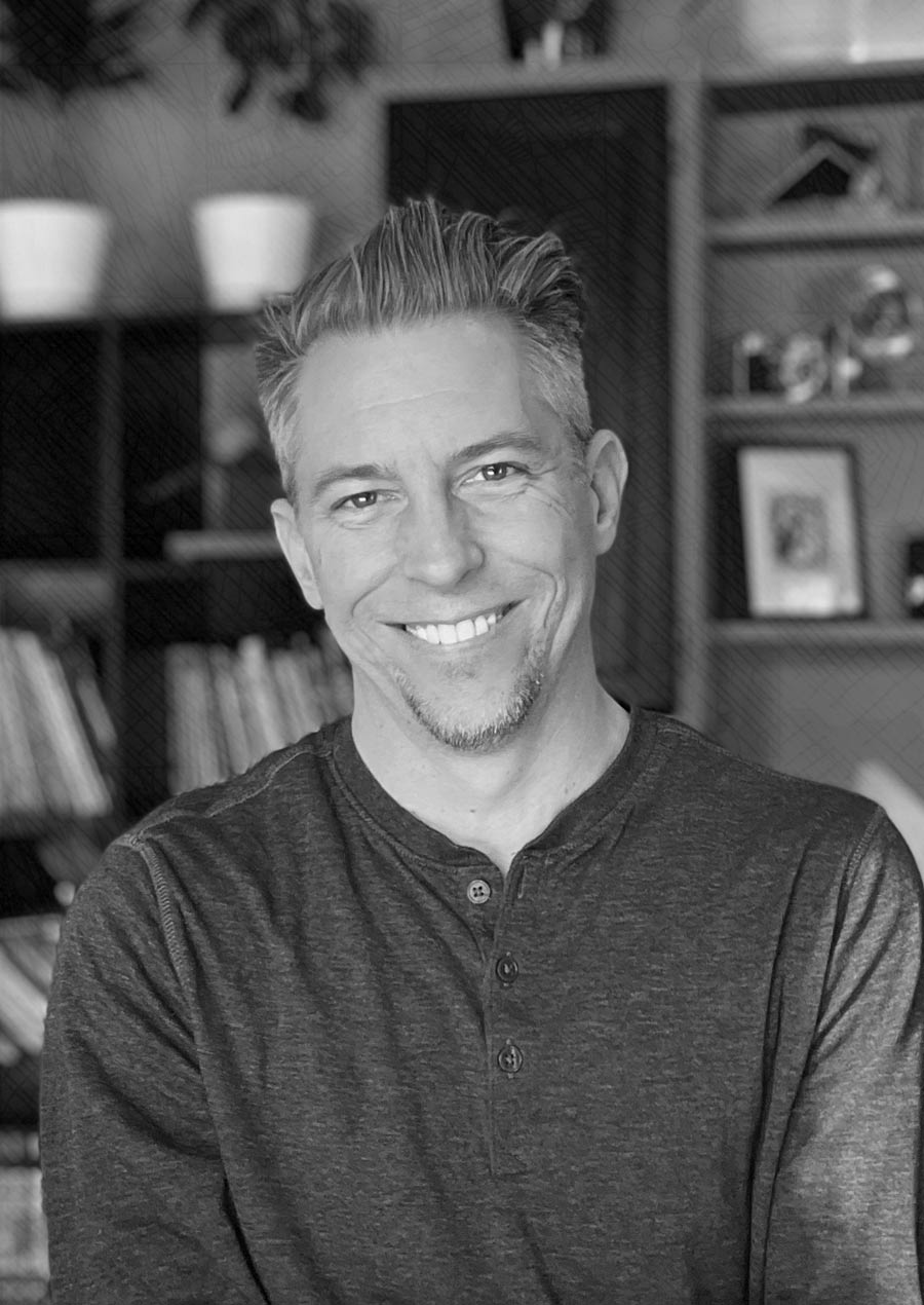 b;acl and white portrait of Michael Ward standing in his office, books, vintage cameras and artwork in the background