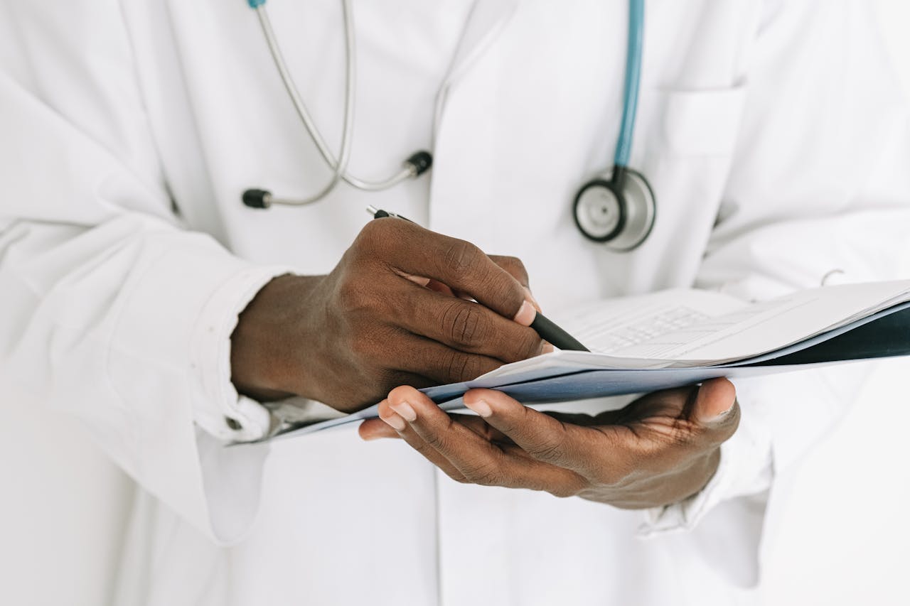 Professional doctor writing on a clipboard with a stethoscope in a medical office